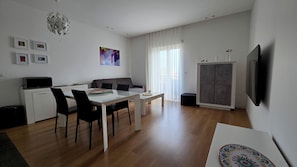 A modern living room with a dining area, a flat-screen TV mounted on the wall, and a ceiling light fixture. - For your vacation in Catania, just a few hundred meters from downtown. (Catania)