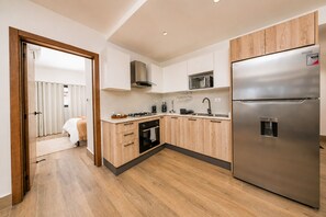 Une cuisine moderne avec des meubles en bois, des appareils électroménagers en acier inoxydable et un four encastré.