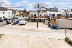 A parking lot with several cars, a building with a wooden deck, and a street with other buildings in the background. - Lovely 2-bedroom condo with parking near H Street / Union Market (Washington)
