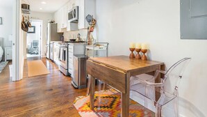 A modern kitchen with wooden flooring, a dining table with chairs, and a colorful rug. - Lovely 2-bedroom condo with parking near H Street / Union Market (Washington)