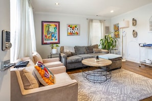 A modern living room with a sofa, armchair, and coffee table. - Lovely 2-bedroom condo with parking near H Street / Union Market (Washington)