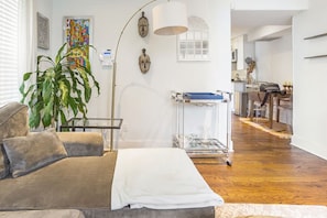 A modern living room with a sofa, a large plant, and a clear glass table with a blue tray. - Lovely 2-bedroom condo with parking near H Street / Union Market (Washington)