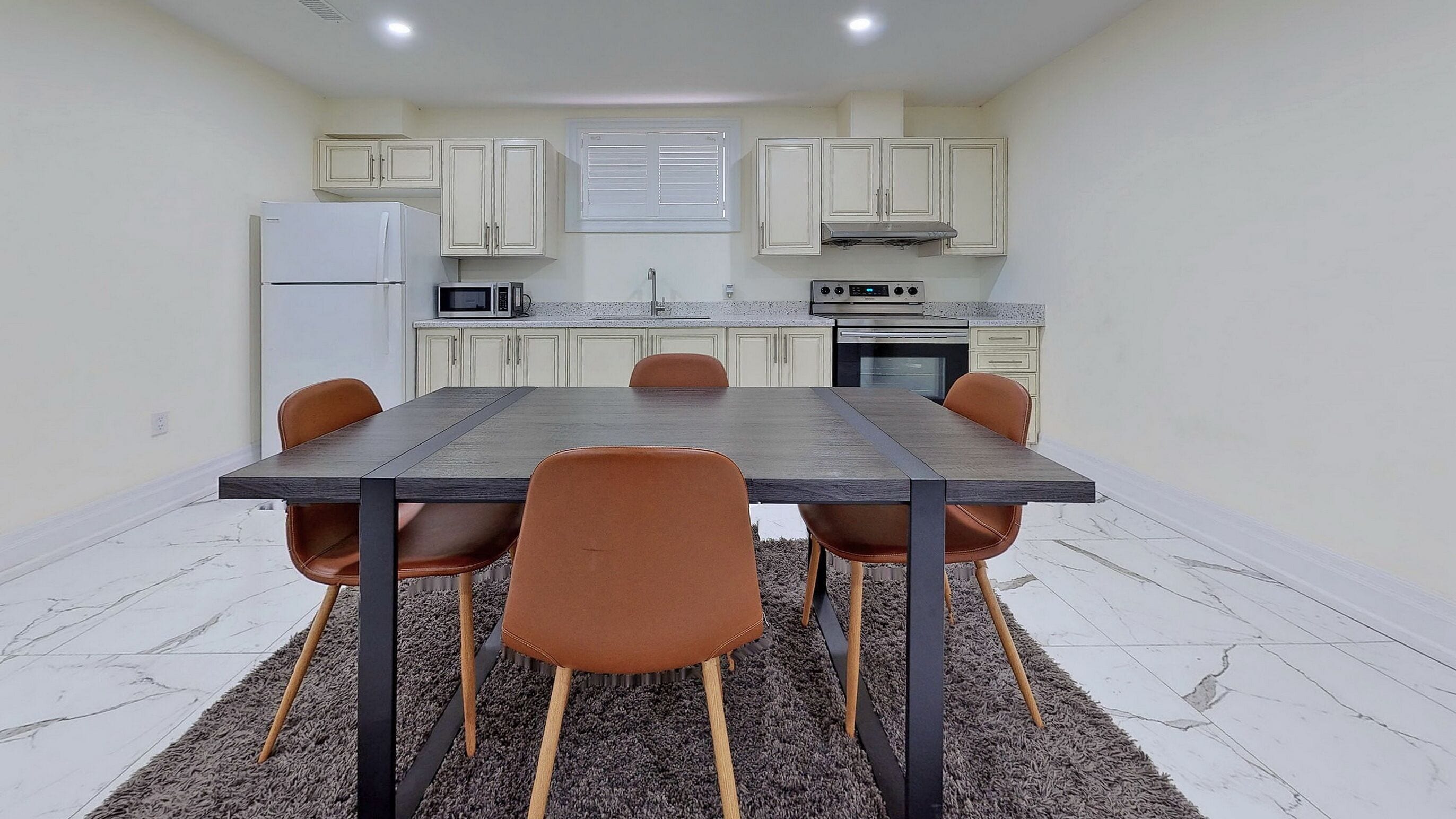 Une cuisine de taille réduite avec des meubles blancs, une table à manger avec des chaises et un réfrigérateur.