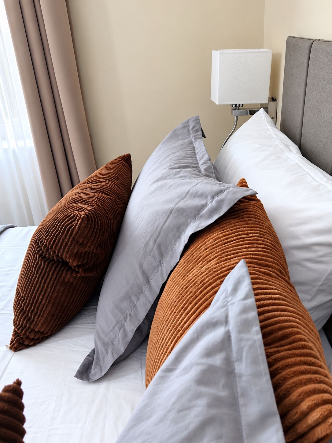 A neatly made bed with multiple pillows in shades of brown and white.