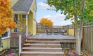 A residential property with a covered patio, a wooden staircase, and a fenced yard.