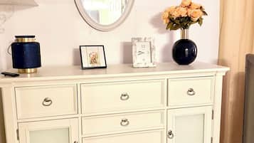 A white dresser with a mirror, a vase with flowers, and a framed picture.
