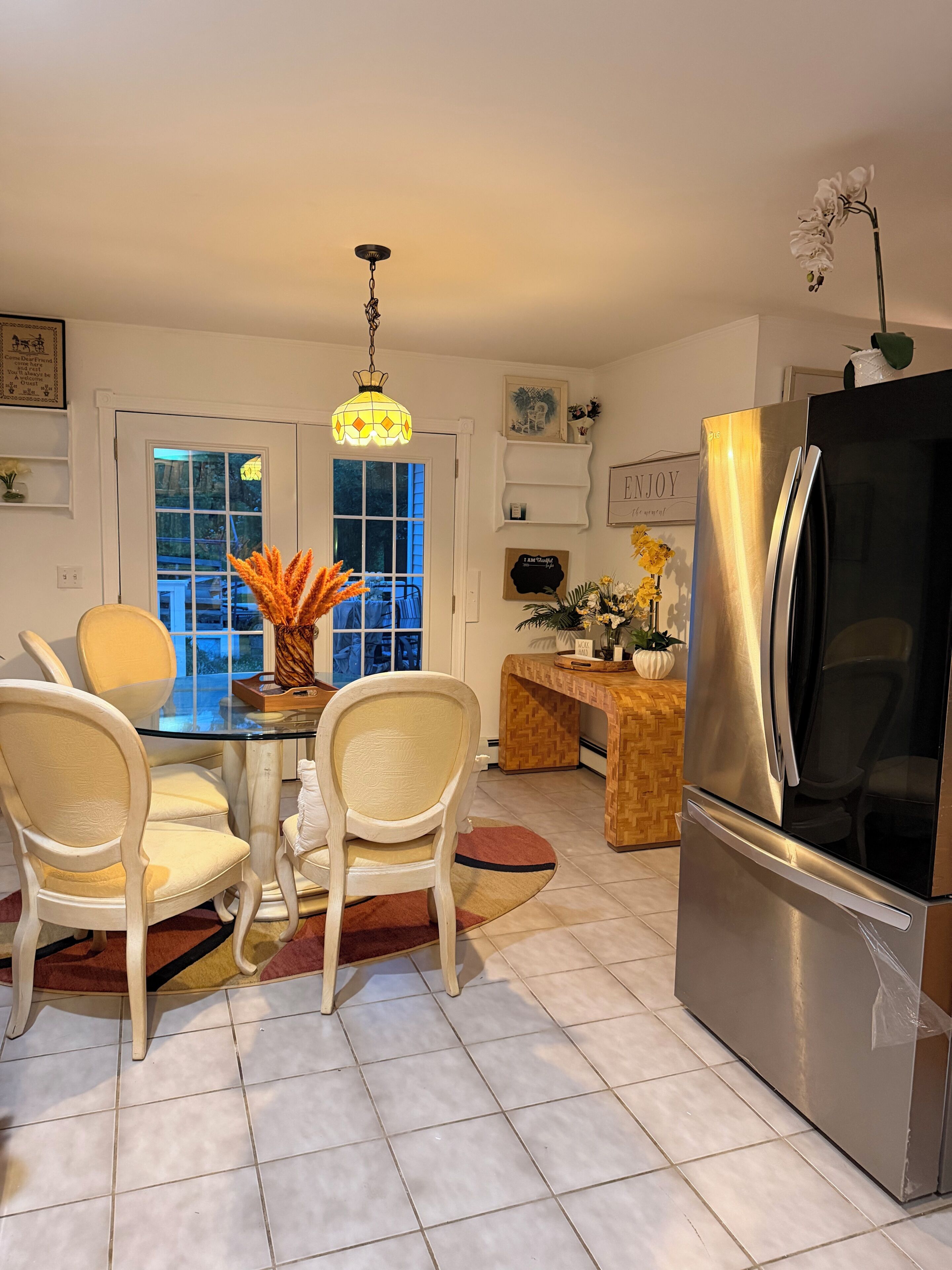 Una cocina moderna con un refrigerador de acero inoxidable, una mesa de comedor con sillas y una lámpara colgante.