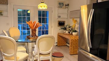 Una cocina moderna con un refrigerador de acero inoxidable, una mesa de comedor con sillas y una lámpara colgante.