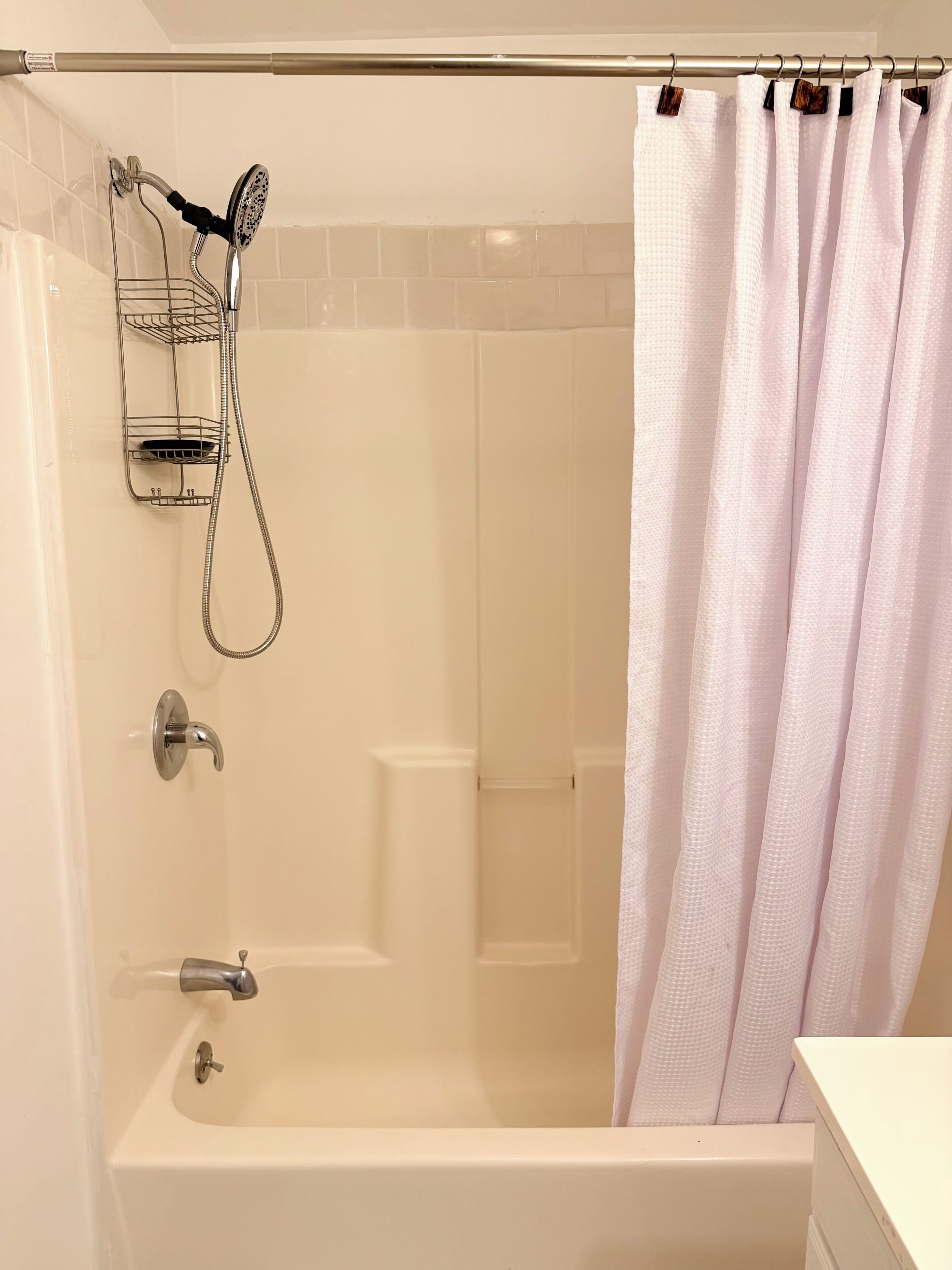 A bathroom with a bathtub, a shower head, and a towel rack.
