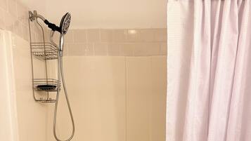 A bathroom with a bathtub, a shower head, and a towel rack.