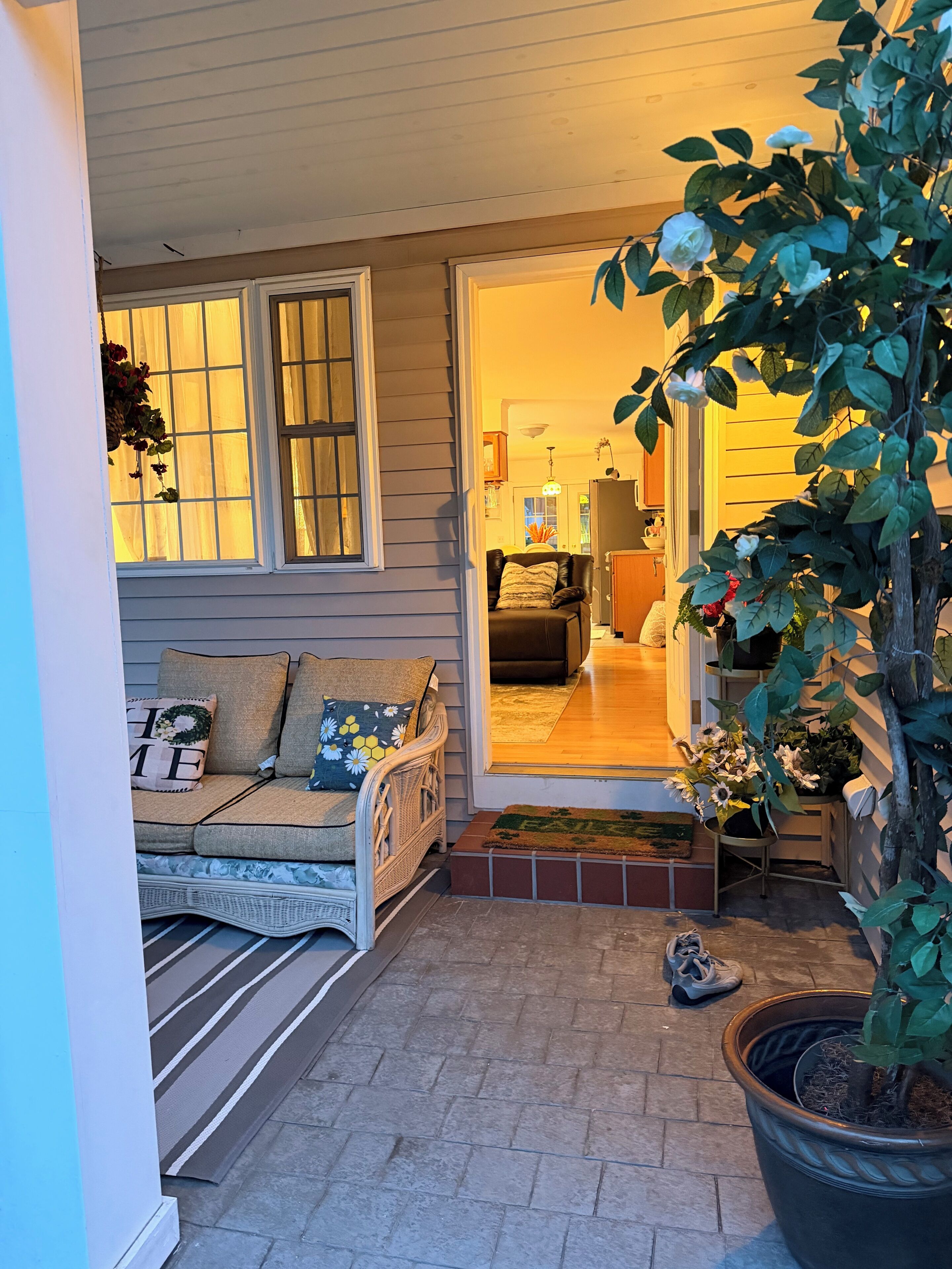 A cozy outdoor seating area with a wicker sofa and a potted plant.