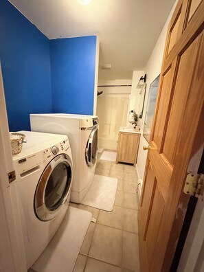 Une buanderie équipée d’un lave-linge, d’un sèche-linge et d’une porte en bois.