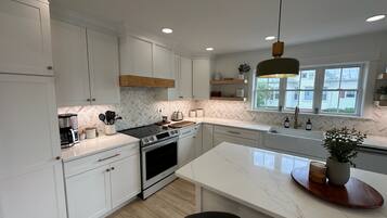 A modern kitchen with white cabinetry, a central island, and a large window.