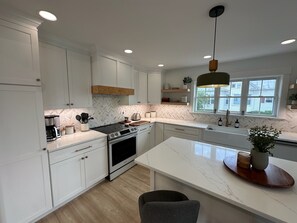 Una cocina moderna con armarios blancos, una isla central y un amplio ventanal.