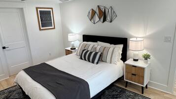 A bedroom with a bed, bedside tables, a ceiling fan, a rug, and wall art.