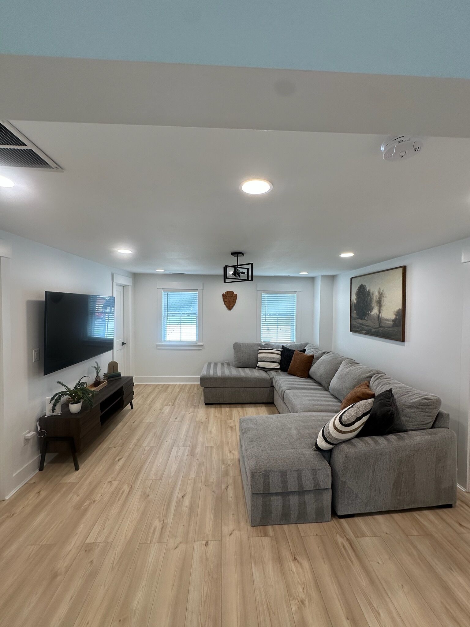 Una sala de estar moderna con un sofá modular, un televisor de pantalla plana y piso de madera.