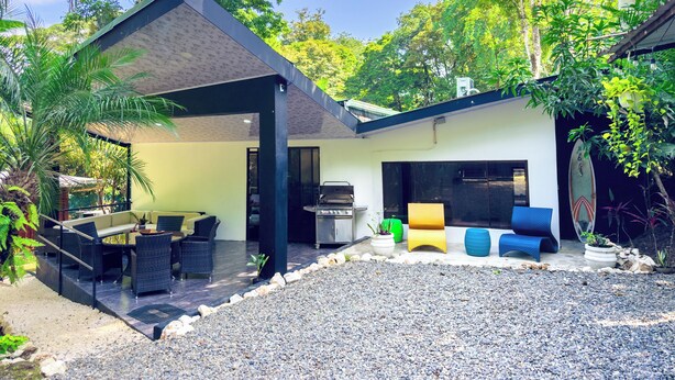 An outdoor patio area with a covered seating area, a grill, and a surfboard. - Mountain House,Beautiful 3-bedroom with AC in quaint Puerto Viejo de Talamanca (Puerto Viejo de Talamanca)