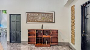 A hallway with a dark wooden door, a marble floor, a wooden cabinet with shelves, and a framed abstract artwork on the wall. - Mountain House,Beautiful 3-bedroom with AC in quaint Puerto Viejo de Talamanca (Puerto Viejo de Talamanca)