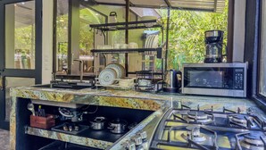 A kitchen with a gas stove, a microwave, and a coffee maker. - Mountain House,Beautiful 3-bedroom with AC in quaint Puerto Viejo de Talamanca (Puerto Viejo de Talamanca)