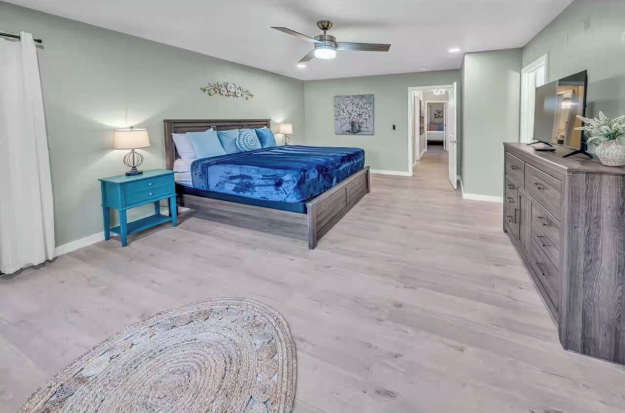 A bedroom with a bed, nightstand, dresser, and a ceiling fan.