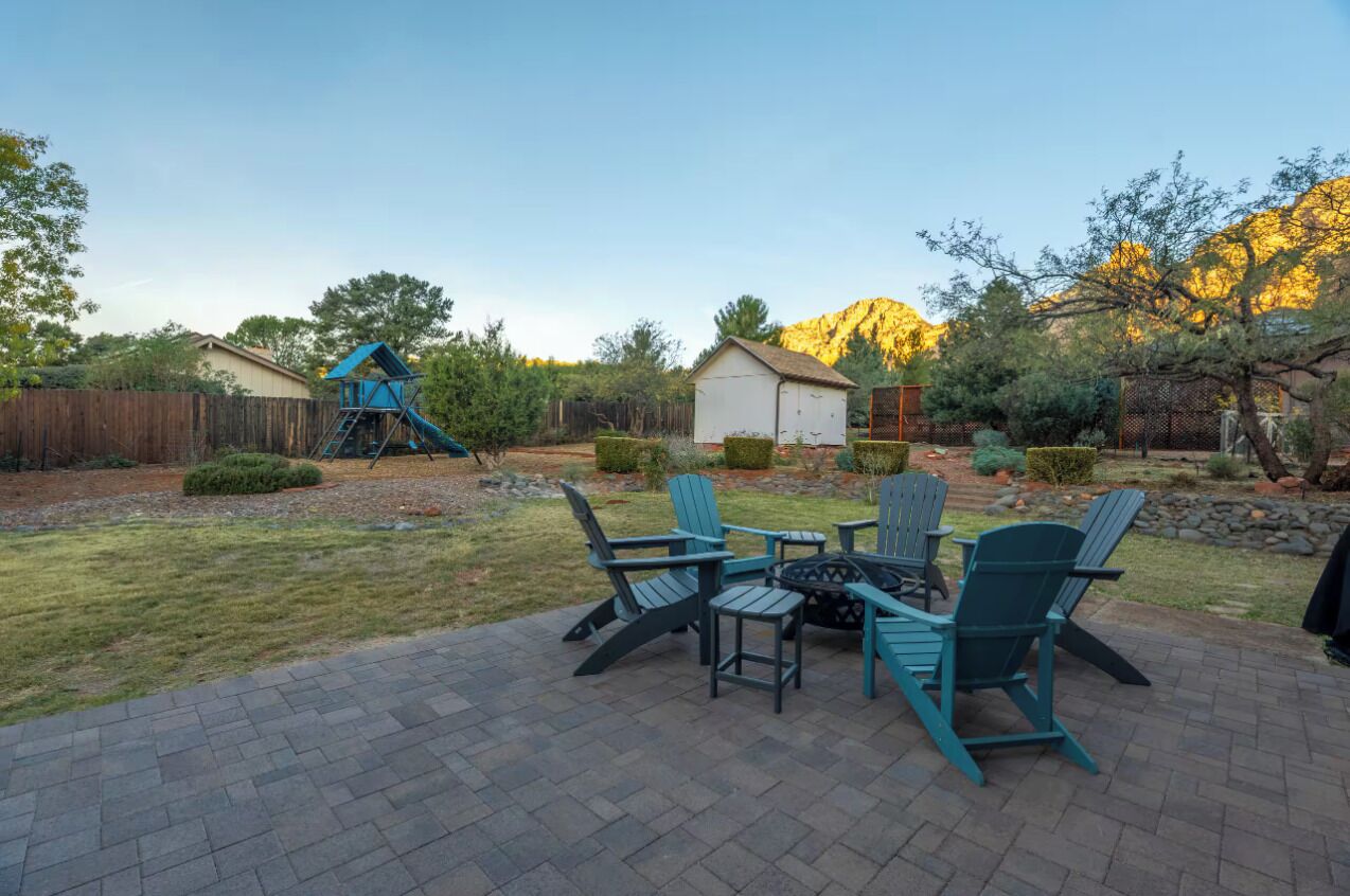 A backyard with a playset, a small shed, and a seating area with chairs and a table.