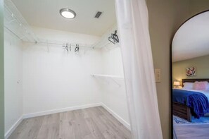 Una habitación con techo blanco, suelo de madera y cama con manta azul.