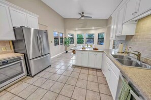 A modern kitchen with stainless steel appliances, white cabinetry, and a central island. - Luxury Red Rock Retreat with Hot Tub, Fire Pit, Game Room and Large Yard (Sedona)