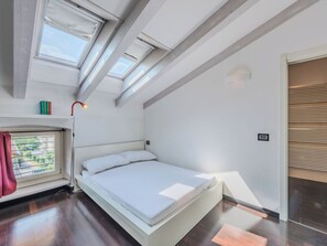 A modern bedroom with a skylight, a bed, a bedside lamp, and a view of the outside. - Le Falesie by Interhome (Arco)
