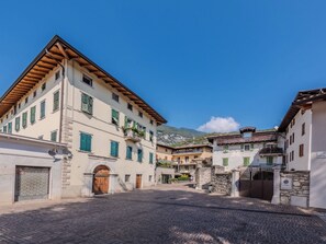 Eine Kopfsteinpflasterstraße in einer historischen Stadt mit traditioneller Bebauung, einem zentralen Platz und einem Berg im Hintergrund.