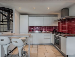 A modern kitchen with white cabinets, a red tiled backsplash, stainless steel appliances, and a black staircase. - Le Falesie by Interhome (Arco)