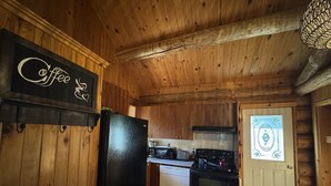 Un interior de madera con una zona de cocina que incluye un refrigerador, estufa y microondas.
