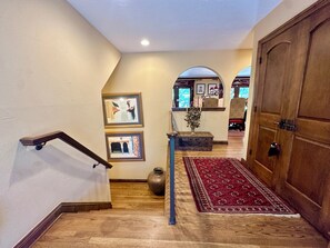 Eine Holztreppe mit Handlauf, einem roten Teppich mit Muster und einem Holzkabinett.