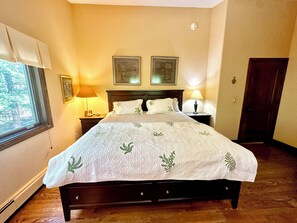 Une chambre à coucher comprenant un lit, deux tables de chevet, une fenêtre avec des rideaux et deux lampes fixées au mur.
