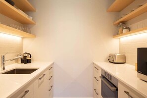 A compact kitchen with a sink, toaster, and cabinets. - Speargrass Villa | Luxury | Hot Tub | Pool (Queenstown)