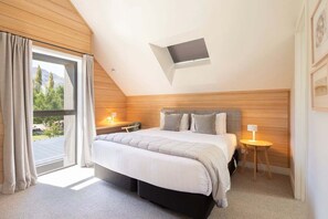 A bedroom with a bed, bedside tables, a window with curtains, and a skylight. - Speargrass Villa | Luxury | Hot Tub | Pool (Queenstown)