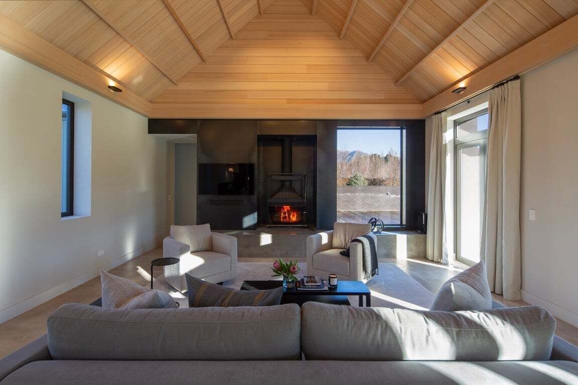 A modern living room with a fireplace, sofas, and a large window.