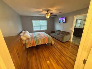 A bedroom with a bed, a sofa, a ceiling fan, a TV, and a window with blinds. - Contractor Preferred: Extended Stay Ready w/ On-Site Laundry & Great Rates (Panama City)