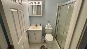 A compact bathroom with a white sink, a toilet, a mirror with lights, and a shower area. - Contractor Preferred: Extended Stay Ready w/ On-Site Laundry & Great Rates (Panama City)