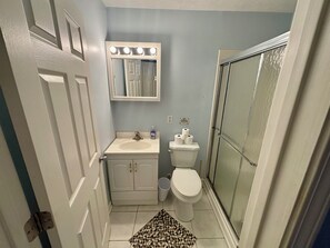 A compact bathroom with a white sink, a toilet, a mirror with lights, and a shower area. - Contractor Preferred: Extended Stay Ready w/ On-Site Laundry & Great Rates (Panama City)