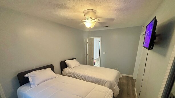 A bedroom with two beds, a ceiling fan, and a television on the wall. - Contractor Preferred: Extended Stay Ready w/ On-Site Laundry & Great Rates (Panama City)