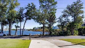 A residential area with a sidewalk, a parked car, and a body of water in the background. - Contractor Preferred: Extended Stay Ready w/ On-Site Laundry & Great Rates (Panama City)