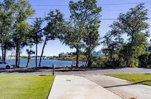 A residential area with a sidewalk, a parked car, and a body of water in the background. - Contractor Preferred: Extended Stay Ready w/ On-Site Laundry & Great Rates (Panama City)