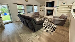 A living room with a fireplace, a ceiling fan, and a clock on the wall. - Contractor Preferred: Extended Stay Ready w/ On-Site Laundry & Great Rates (Panama City)