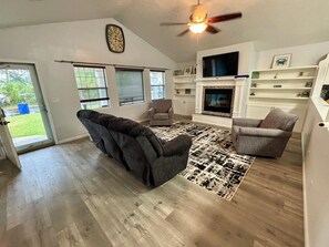 A living room with a fireplace, a ceiling fan, and a clock on the wall. - Contractor Preferred: Extended Stay Ready w/ On-Site Laundry & Great Rates (Panama City)
