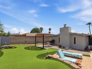 Ein Garten mit Terrasse, Grill und Schwimmbad.