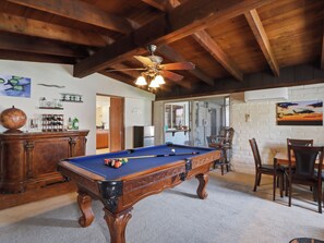 A pool table in a room with wooden beams, a ceiling fan, and a dining area with chairs and a table. - New Relaxing 3 Bedroom Desert Oasis with Sparkling Pool! (Tucson)