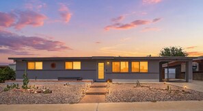 A modern house with a flat roof, multiple windows, and a well-maintained garden with cacti. - New Relaxing 3 Bedroom Desert Oasis with Sparkling Pool! (Tucson)