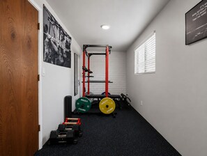Ein Heimfitnessraum mit Squat-Rack, Gewichtsplatten und Kurzhanteln.