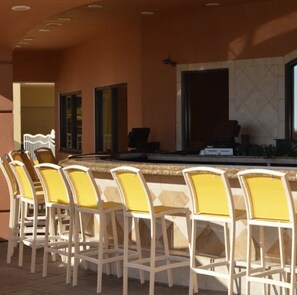 An outdoor bar area with white chairs and a counter. - Beautiful condo with amazing view located in Emerald Grande at the Harborwalk. (Destin)