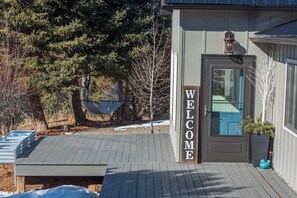 A wooden deck with a welcome sign, a hammock, and a house with a blue door. - Mountain Views of the San Juans. Great outdoor living, near bike, hike and swim. (Ridgway)